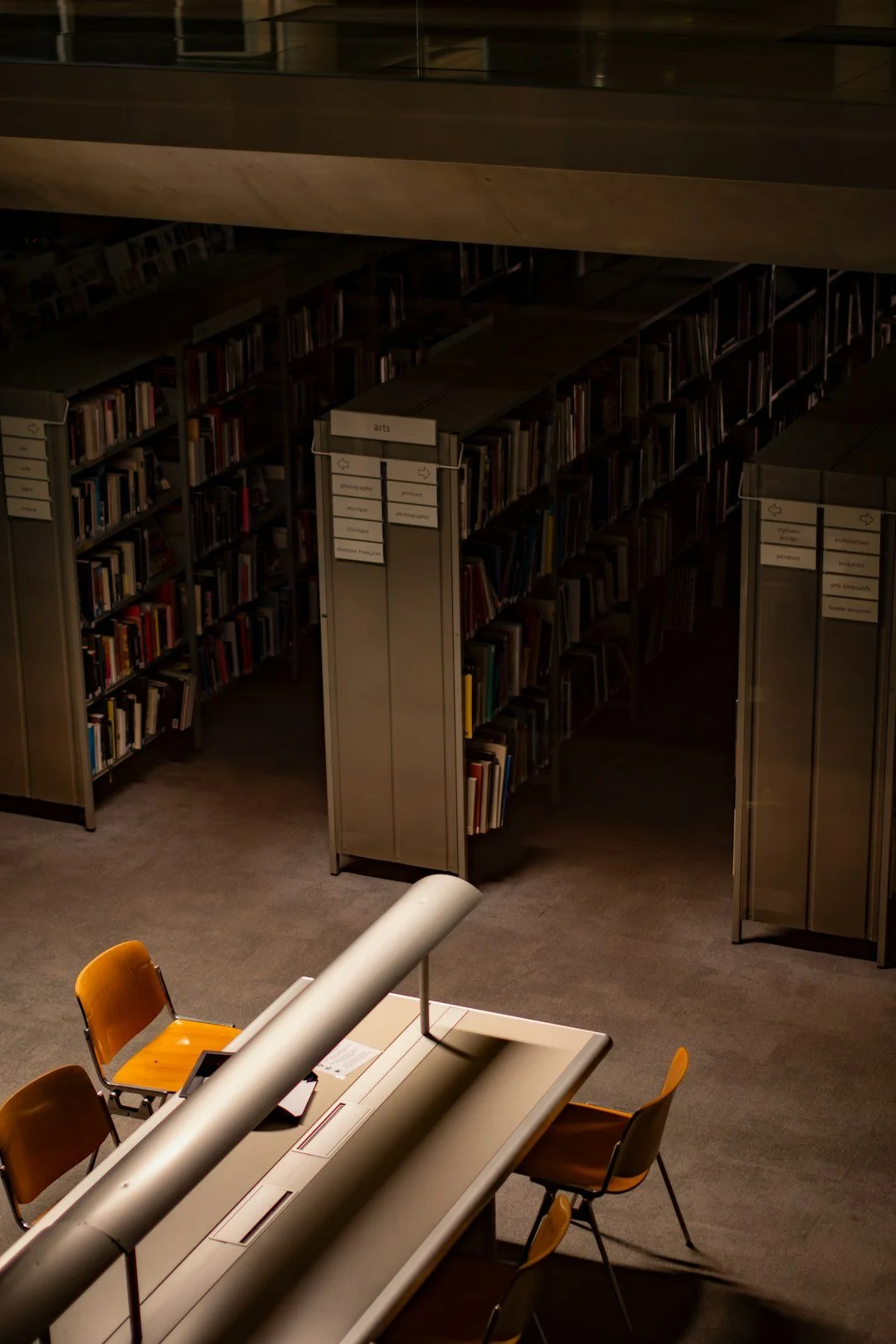 Quiet library stacks with a single lit desk