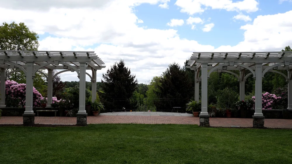 Lawn Garden with white pergola colonnade and blue sky at Tower Hill Botanic Garden wedding venue in Boylston, MA