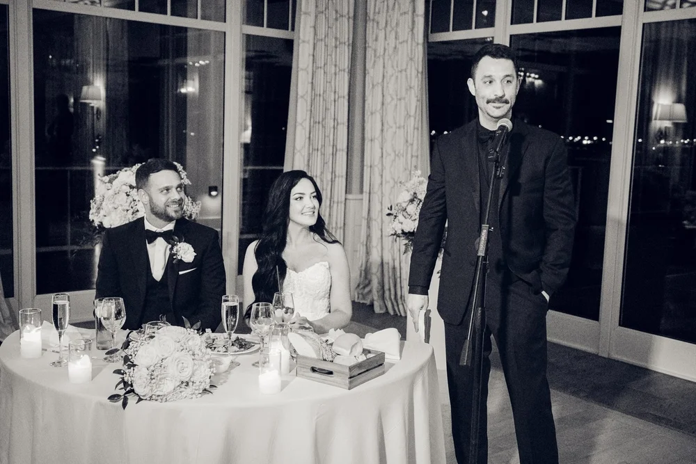Beauport Hotel wedding videographer, Gloucester, MA — black-and-white toast at the sweetheart table with the harbor windows behind the couple