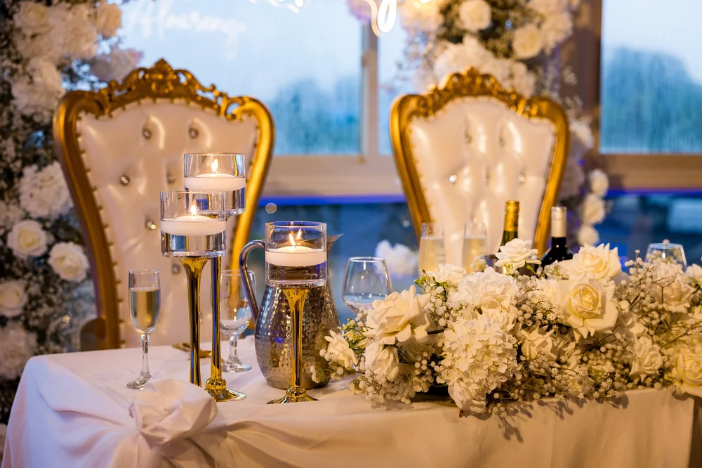 Anthony's Ocean View wedding videographer, New Haven, CT — sweetheart table with gold throne chairs, floating candles, and white roses