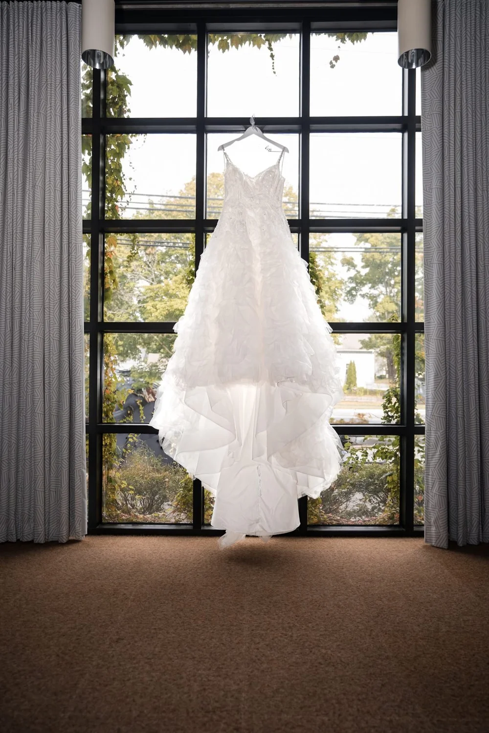 Aldrich Mansion wedding photographer, Warwick, RI — ruffled white bridal gown hanging in the tall grid window before the ceremony