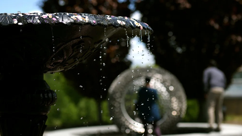 Stone garden fountain water feature with a circular glass ornament at Tower Hill Botanic Garden in Boylston, MA