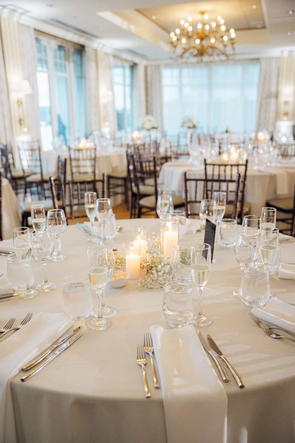 Beauport Hotel wedding photographer, Gloucester, MA — candlelit round table set with white florals and gold chargers in the Grand Ballroom