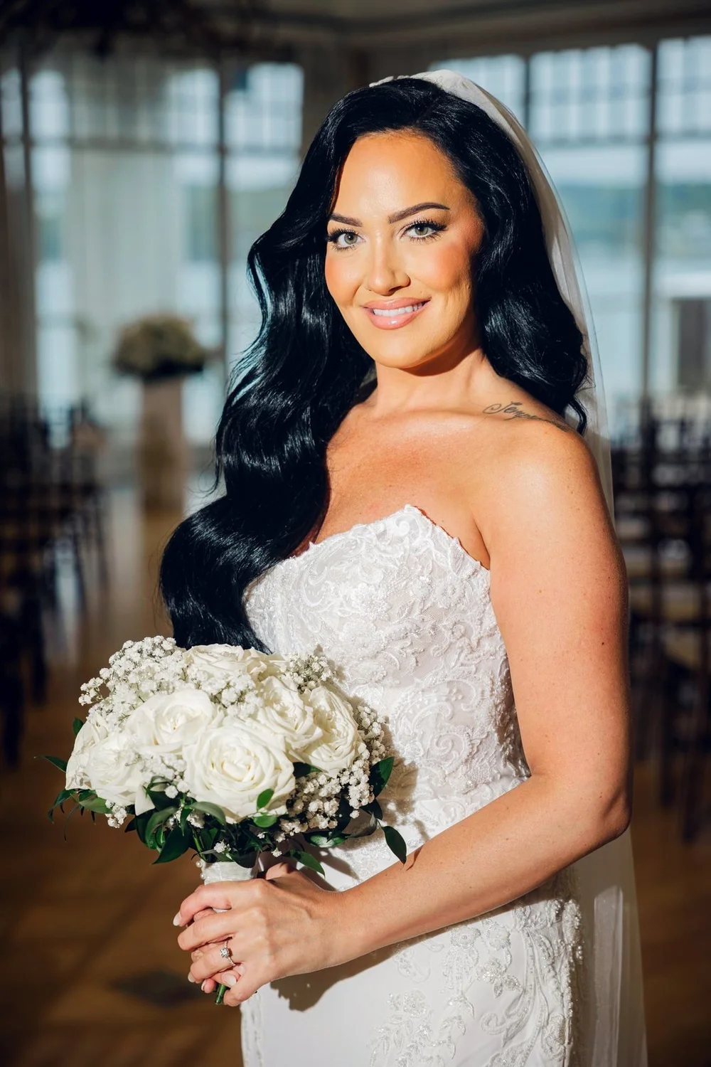 Beauport Hotel wedding photographer, Gloucester, MA — bridal portrait with a white rose bouquet in front of the harbor windows