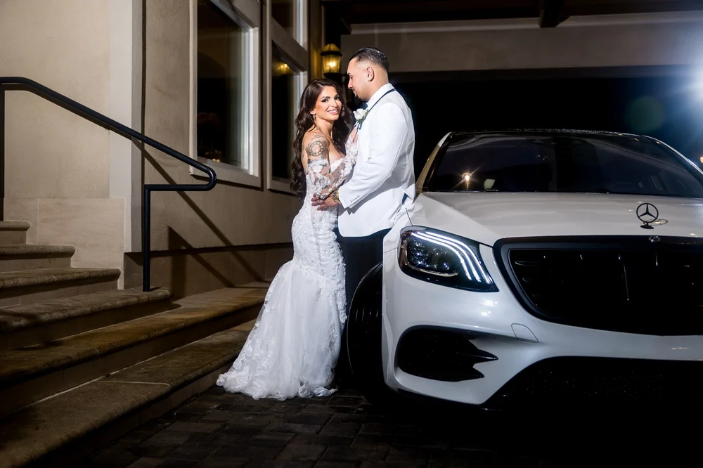Anthony's Ocean View wedding photographer, New Haven, CT — night portrait of the bride and groom beside a white luxury sedan at the entrance