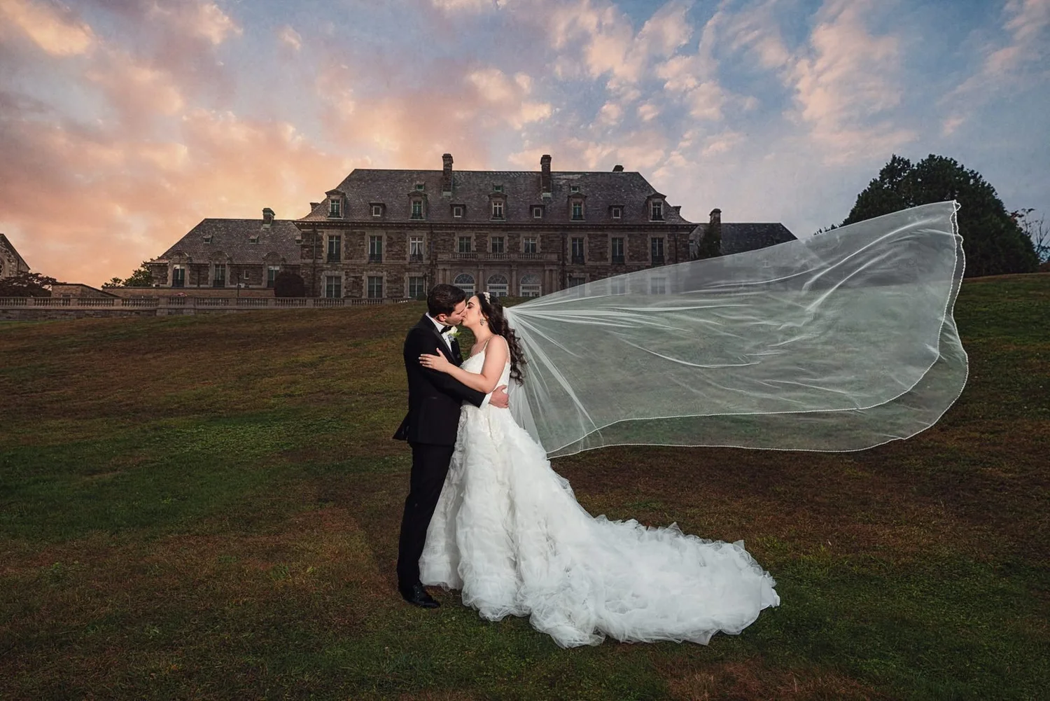Aldrich Mansion wedding photographer, Warwick, RI — bride and groom kissing on the lawn in front of the 70-room French chateau at sunset