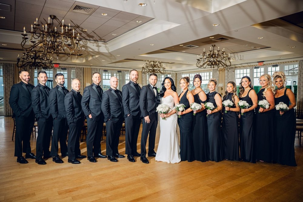Beauport Hotel wedding videographer, Gloucester, MA — bridal party in black lined up beneath the antiqued gold chandeliers of the Oceanside Grand Ballroom