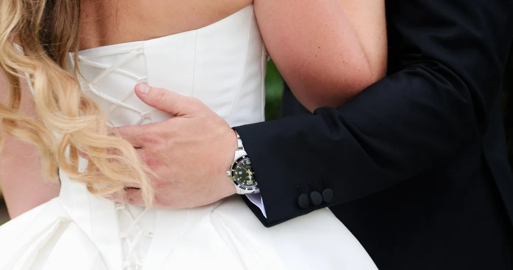 The Gardens at Elm Bank wedding photographer, Wellesley, MA — close-up of groom's hand on the corset lacing of the wedding gown