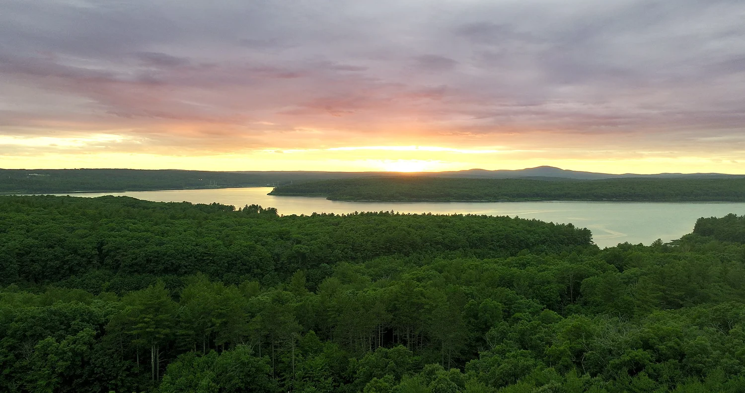 Color-edited sunset aerial drone view of the Wachusett Reservoir and autumn forest canopy at New England Botanic Garden at Tower Hill in Boylston, MA