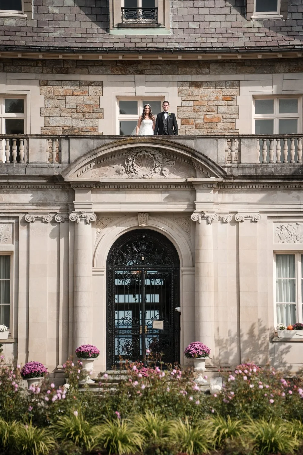Aldrich Mansion wedding photographer, Warwick, RI — bride and groom standing on the limestone balcony above the wrought-iron front entrance