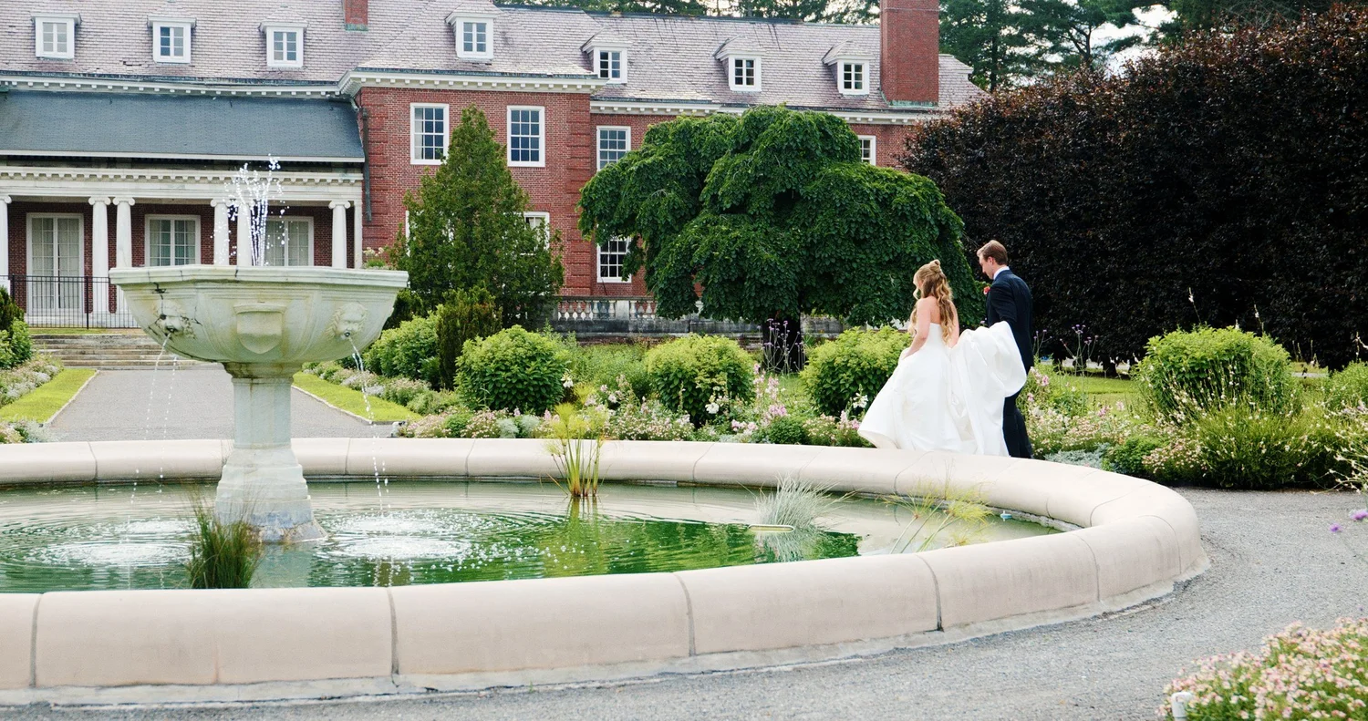 The Gardens at Elm Bank wedding photographer, Wellesley, MA — bride and groom walking past the Italianate Garden fountain in front of the Manor House