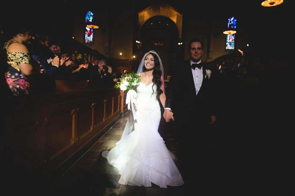 Aldrich Mansion wedding photographer, Warwick, RI — newlyweds smiling down the chapel aisle beneath stained-glass windows