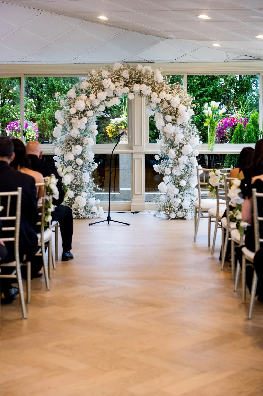 Anthony's Ocean View wedding videographer, New Haven, CT — indoor ceremony space with a white floral arch and gold Chiavari chairs