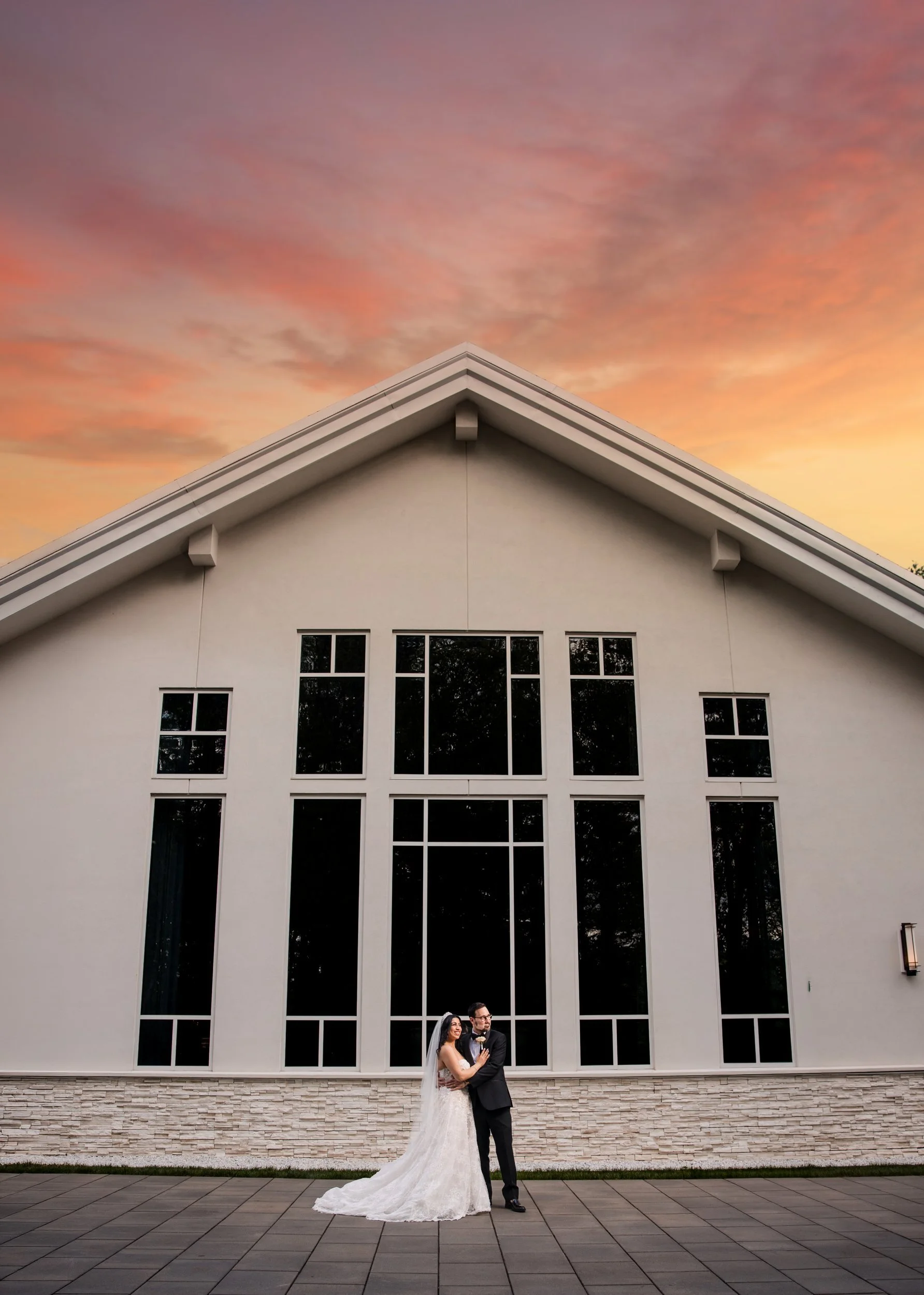 Couple at sunset before Lakeview Pavilion's tall ballroom windows, Foxborough, Massachusetts
