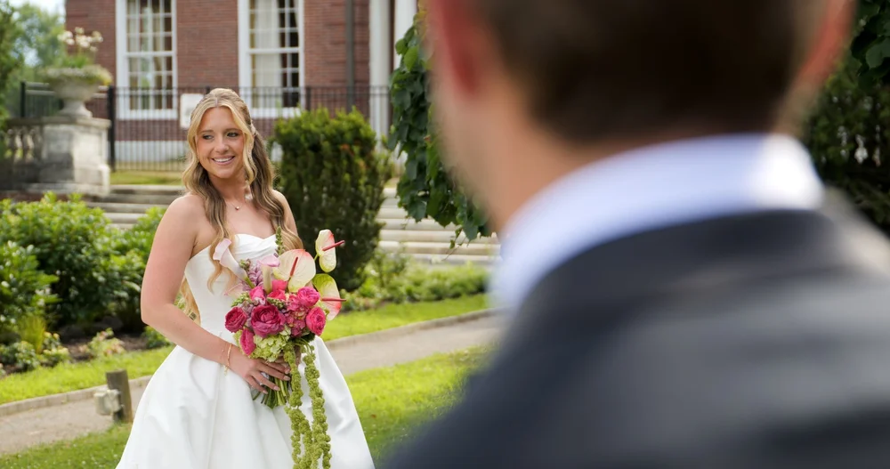 The Gardens at Elm Bank wedding videographer, Wellesley, MA — bride smiling during the first look in front of the brick Manor House
