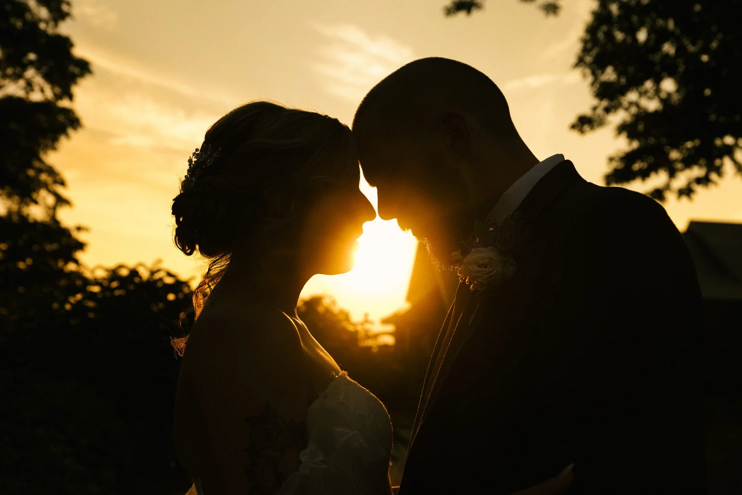 Golden-hour sunset silhouette of the bride and groom touching foreheads at New England Botanic Garden at Tower Hill, Boylston, MA