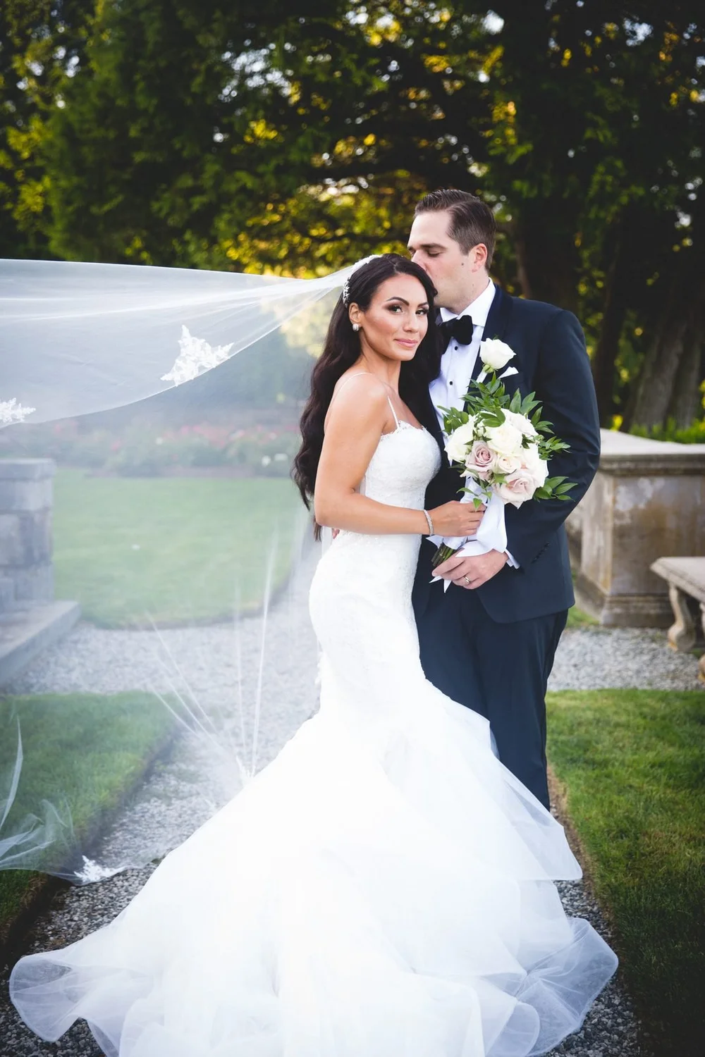 Aldrich Mansion wedding videographer, Warwick, RI — groom kissing the bride's forehead on the garden path at golden hour