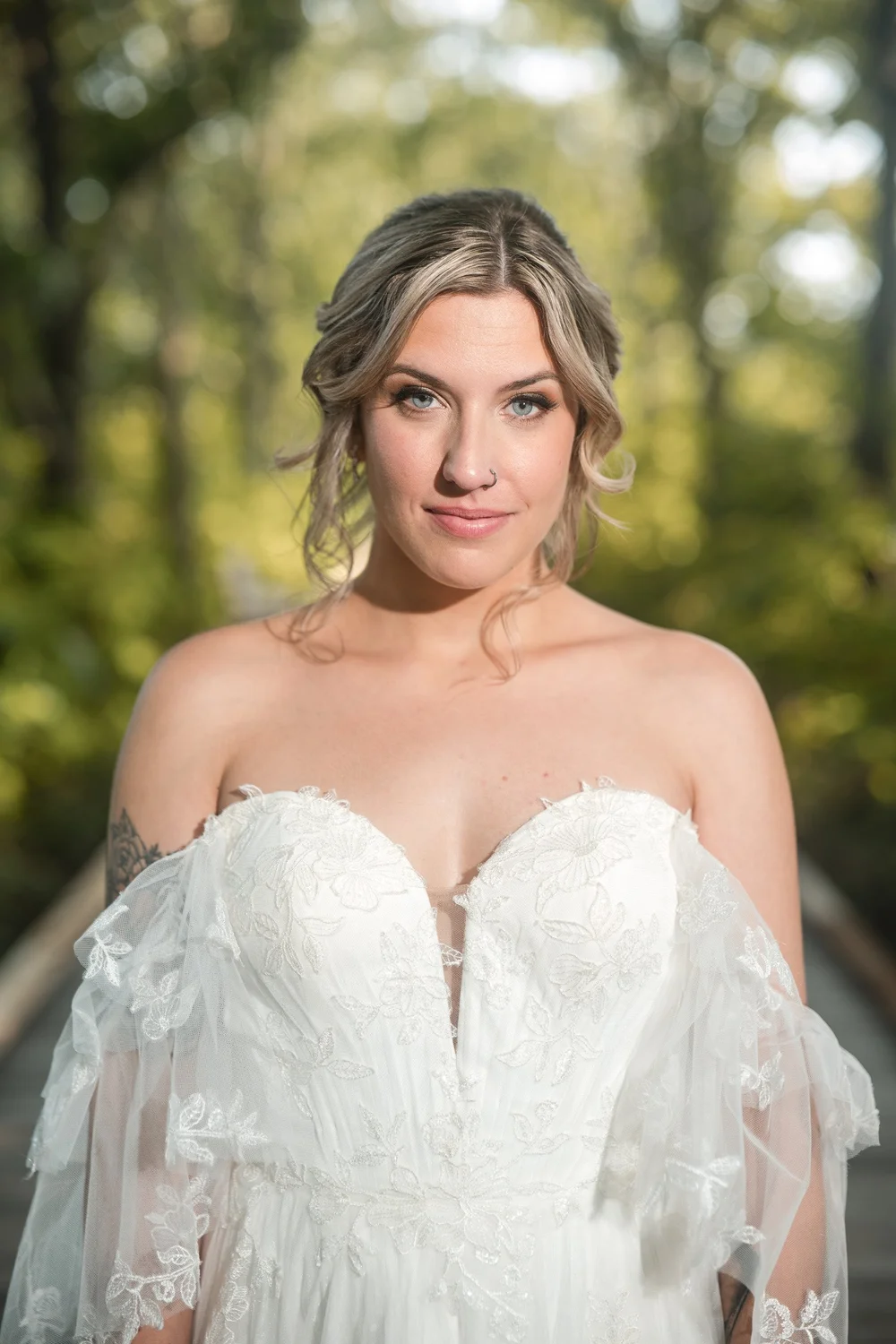 Bridal portrait on a wooden boardwalk path surrounded by sunlit trees at New England Botanic Garden at Tower Hill, Boylston, MA