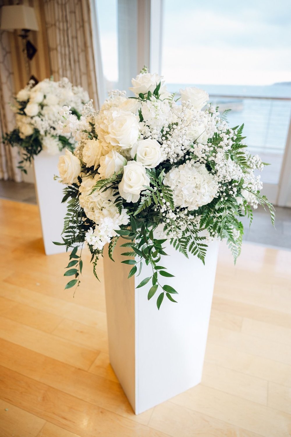 Beauport Hotel wedding photographer, Gloucester, MA — white rose and hydrangea ceremony arrangement in front of the ballroom windows