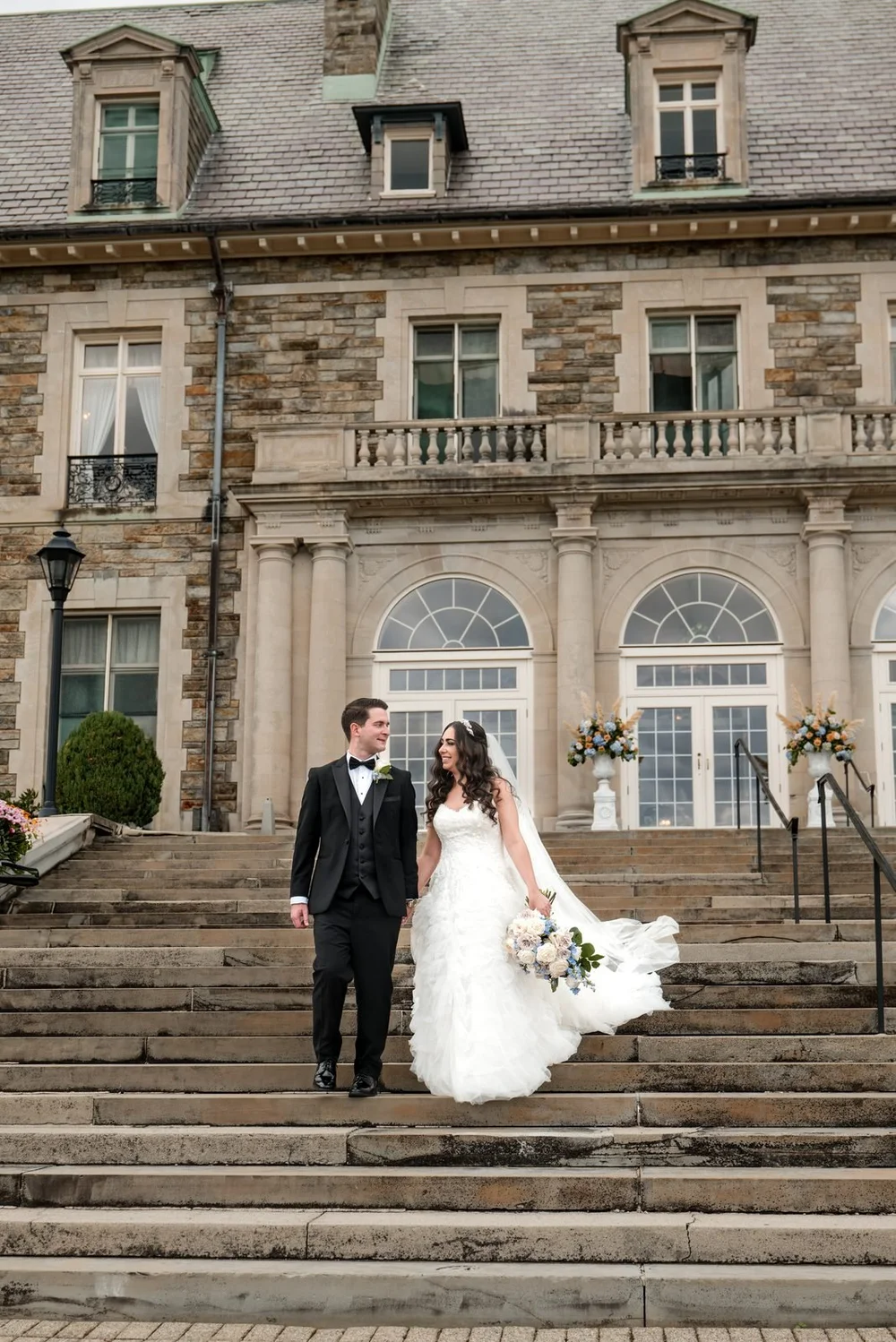 Aldrich Mansion wedding photographer, Warwick, RI — bride and groom walking hand in hand down the grand stone steps of the French chateau