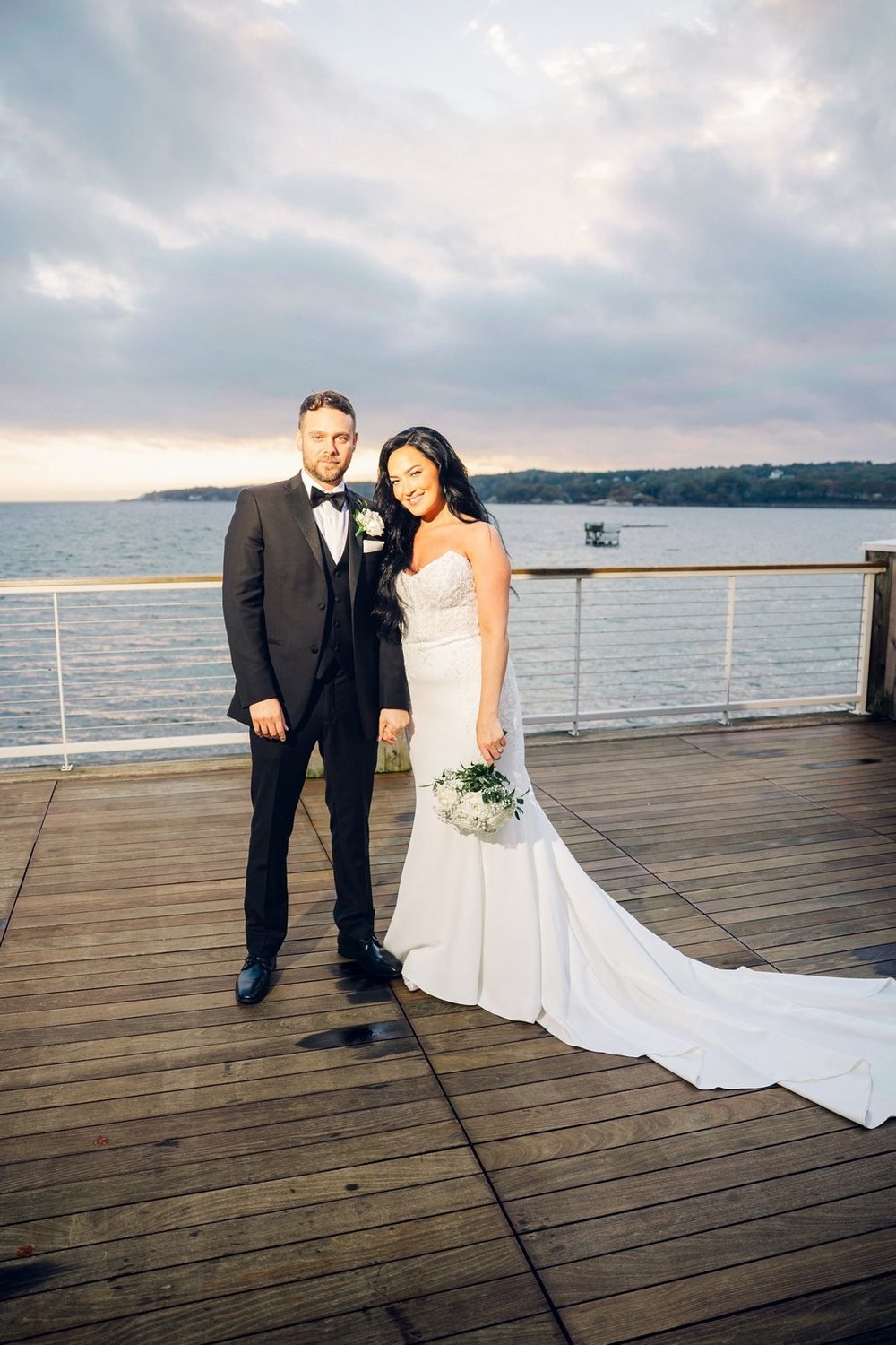 Beauport Hotel wedding videographer, Gloucester, MA — bride and groom on the deck railing at dusk over Gloucester Harbor