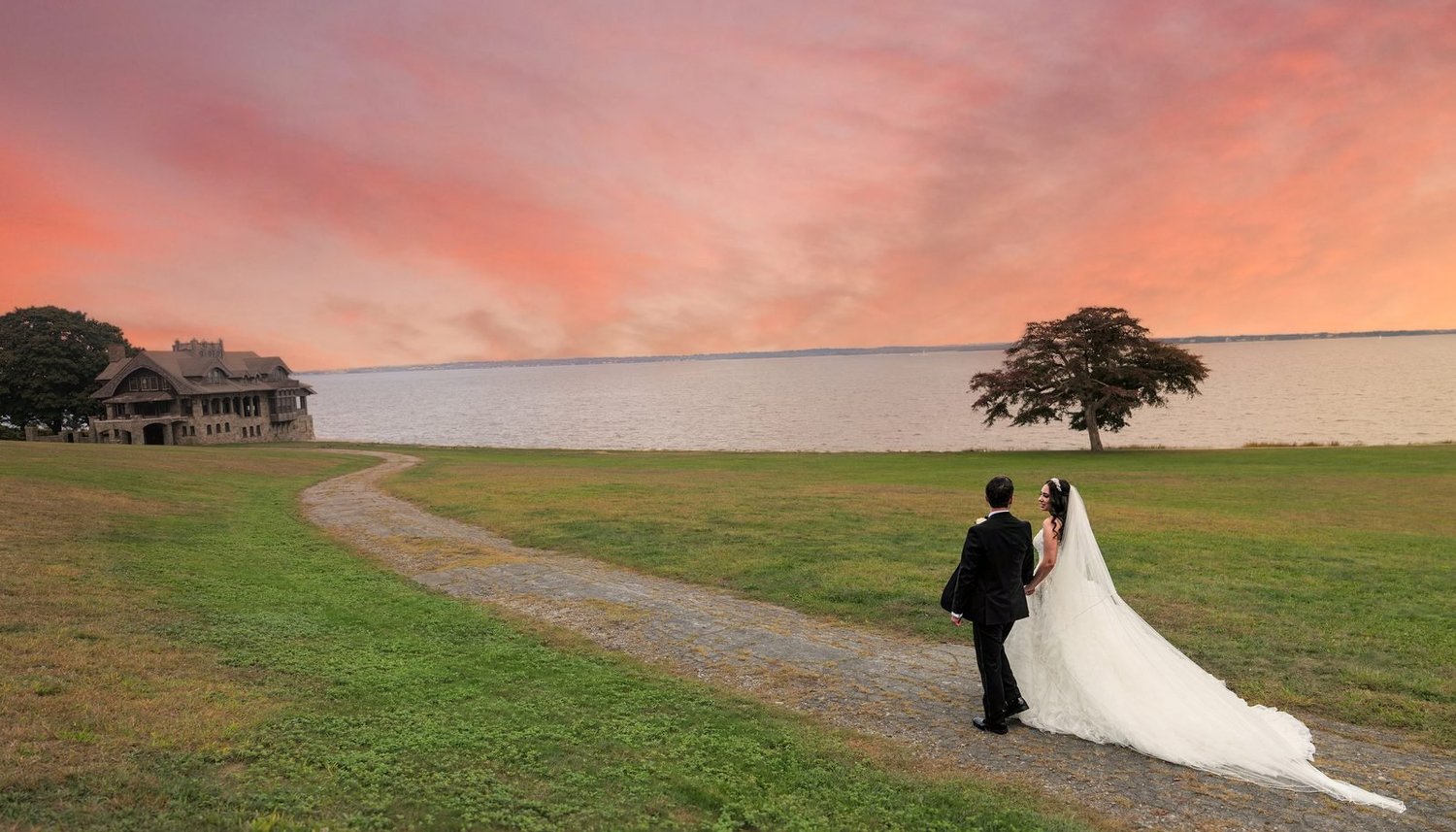 Aldrich Mansion wedding videographer, Warwick, RI — bride and groom walking along the Narragansett Bay shoreline lawn under a pink sunset sky