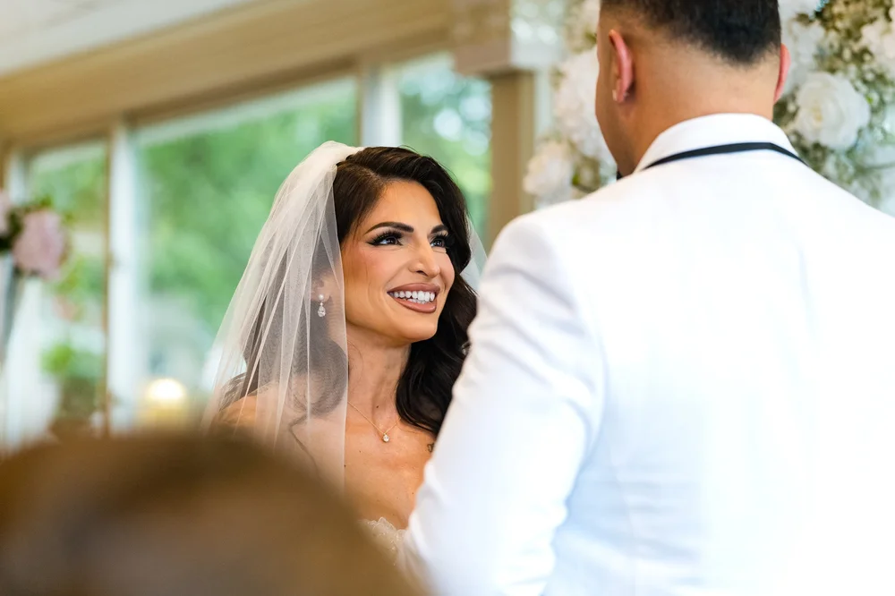 Anthony's Ocean View wedding photographer, New Haven, CT — bride smiling during ceremony vows in the sunlit waterfront pavilion