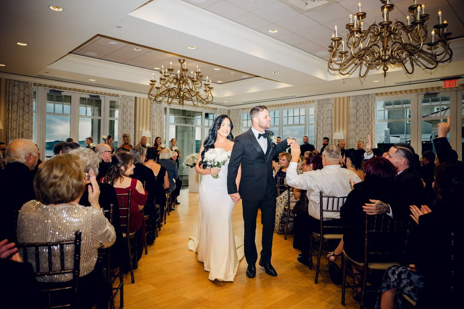 Beauport Hotel wedding photographer, Gloucester, MA — newlyweds recessing down the ballroom aisle as guests cheer under the chandeliers