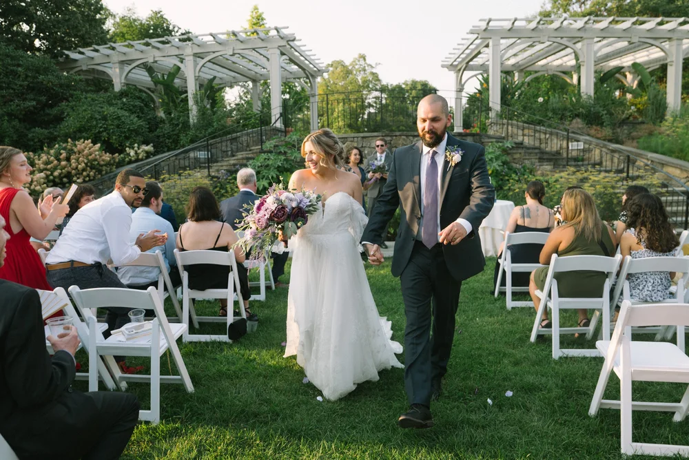 Wedding ceremony recessional down the Lawn Garden aisle between twin white pergolas as guests cheer at New England Botanic Garden at Tower Hill, Boylston, MA