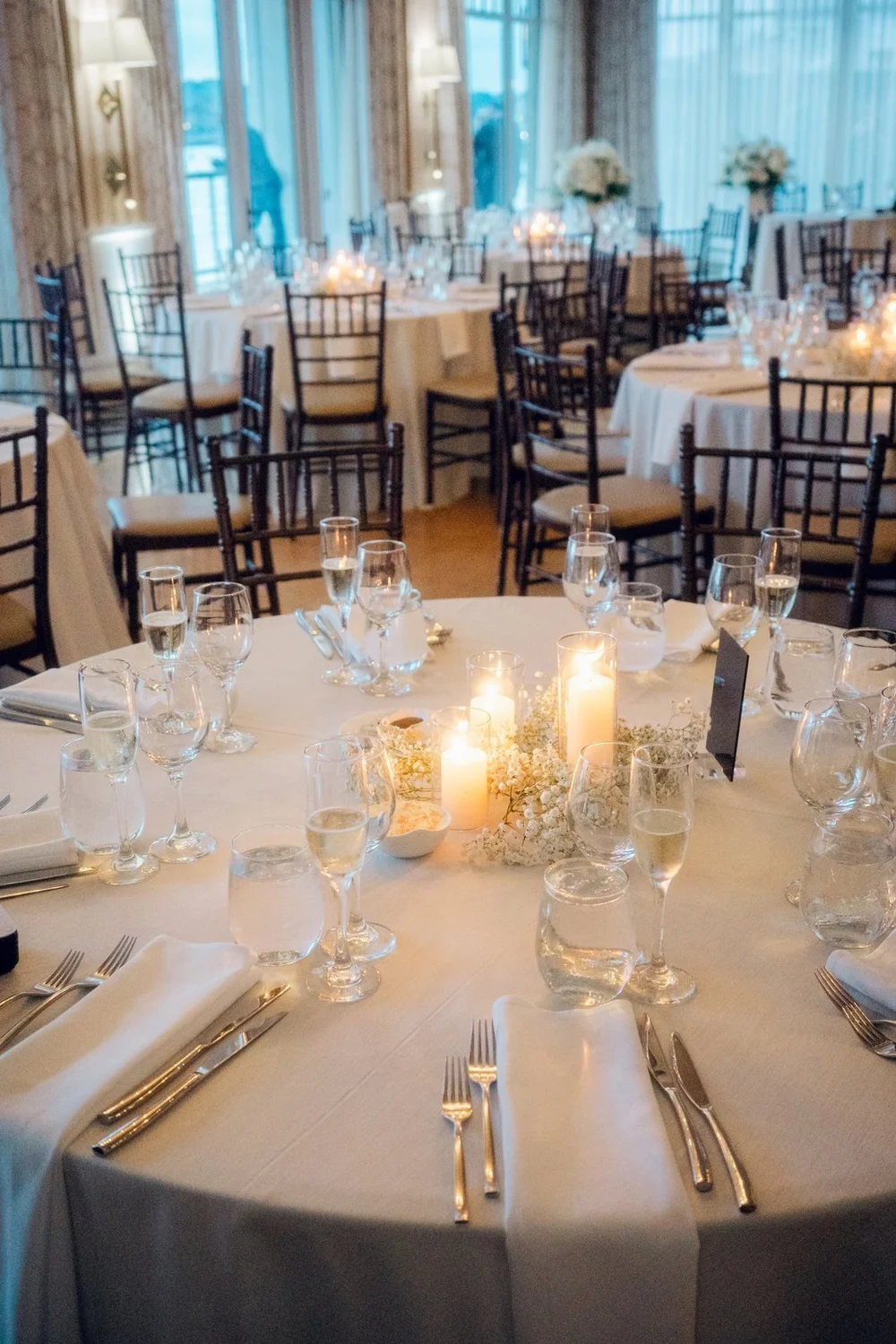 Beauport Hotel wedding videographer, Gloucester, MA — reception tablescape with candles and the ballroom windows beyond