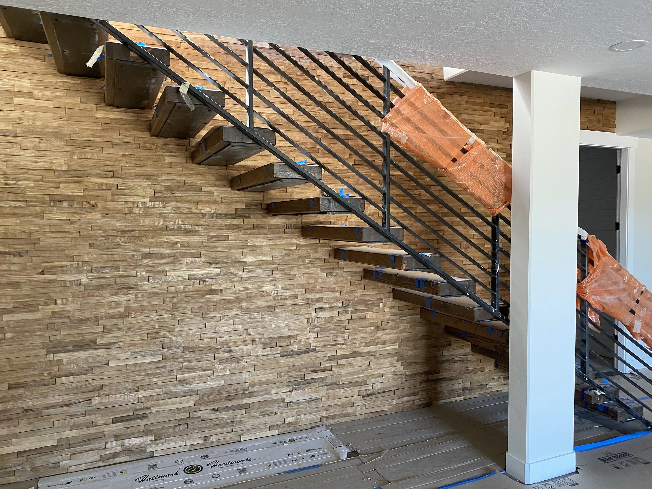 Floating wood tread staircase with steel railing and wood accent wall