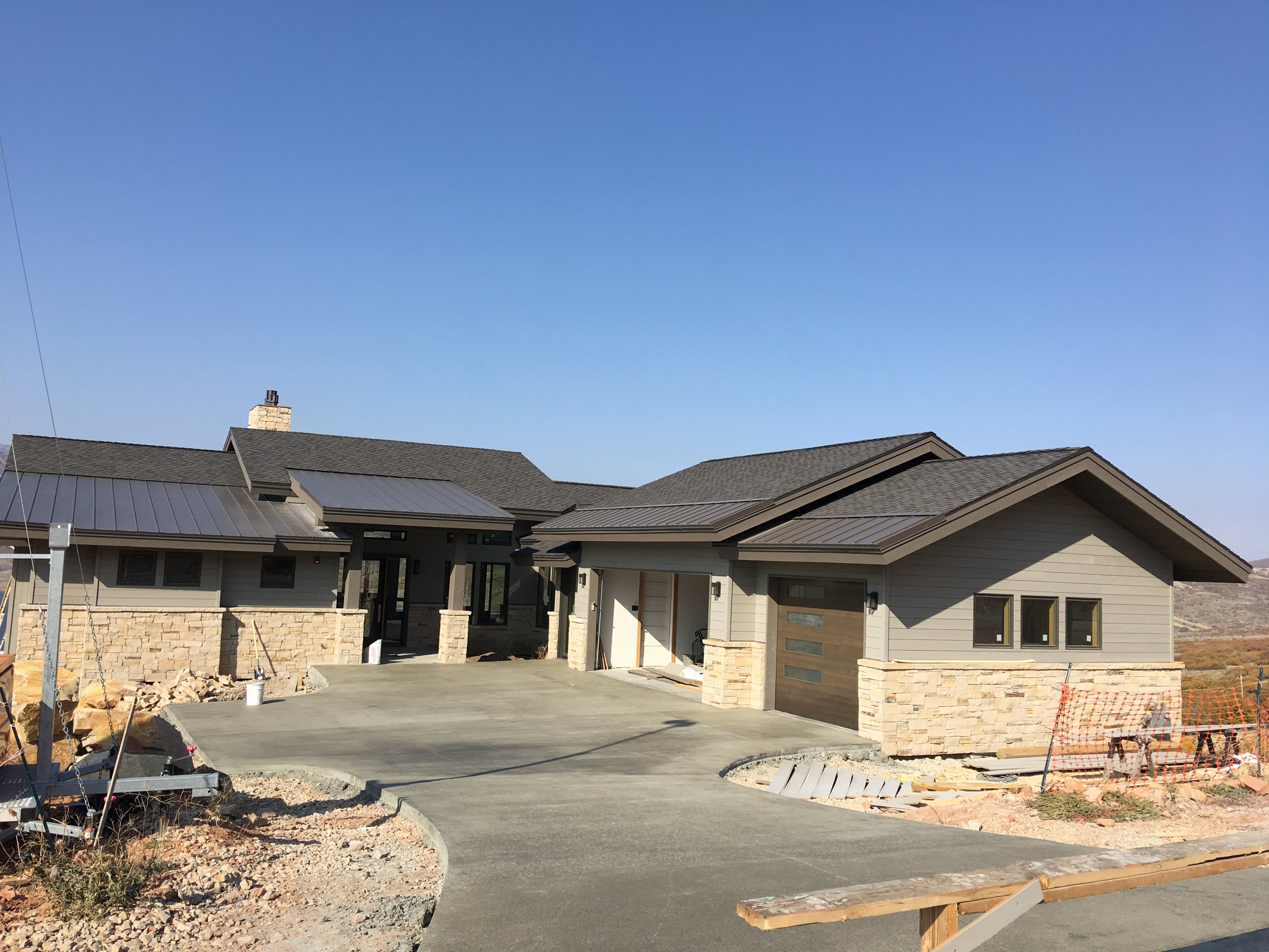 Completed custom home exterior with stone veneer and concrete driveway