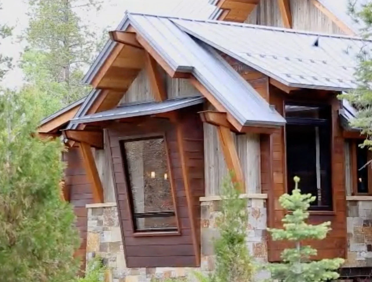 Mountain home exterior with timber brackets, stone veneer, and metal roof