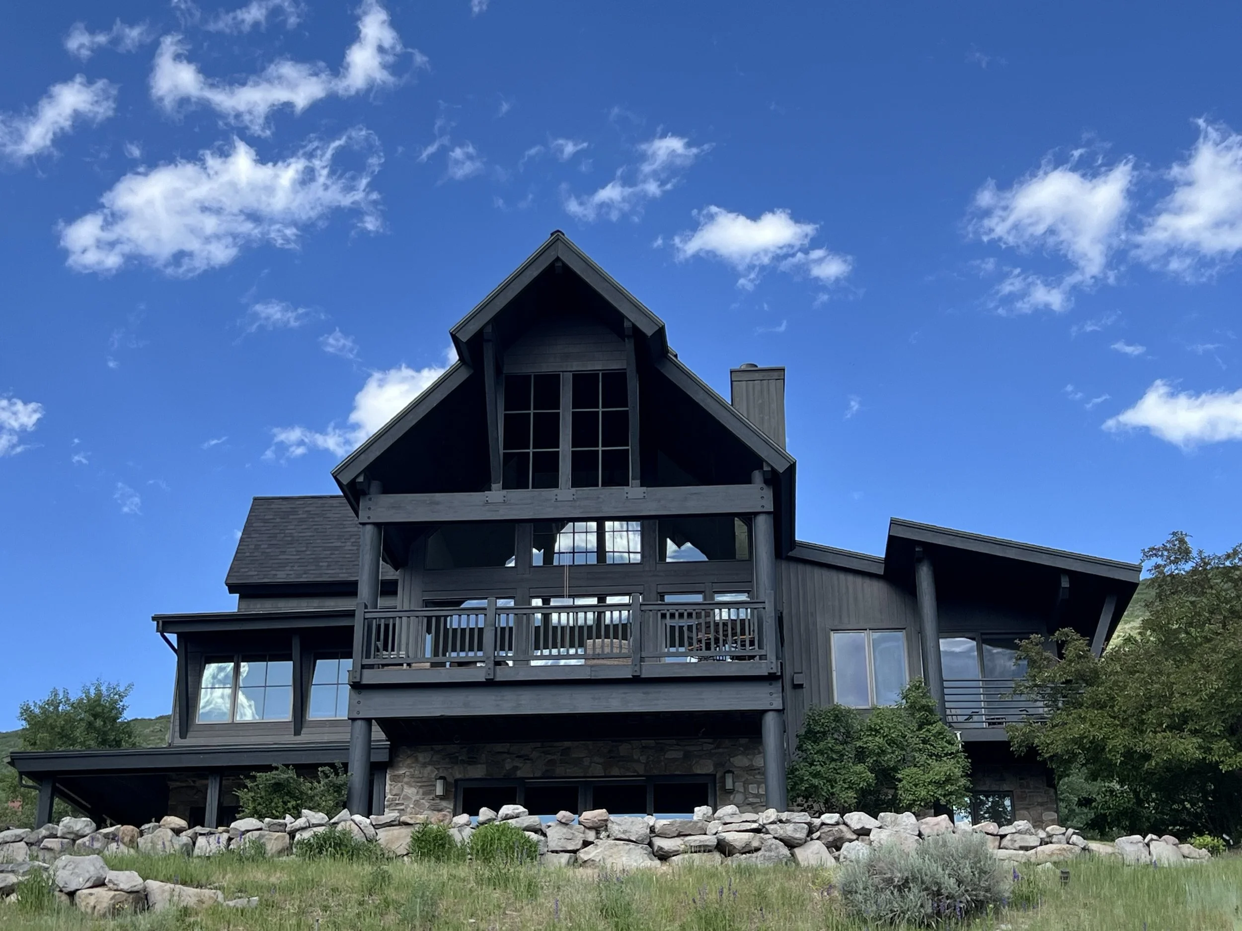 Completed modern mountain home with dark siding and stone base