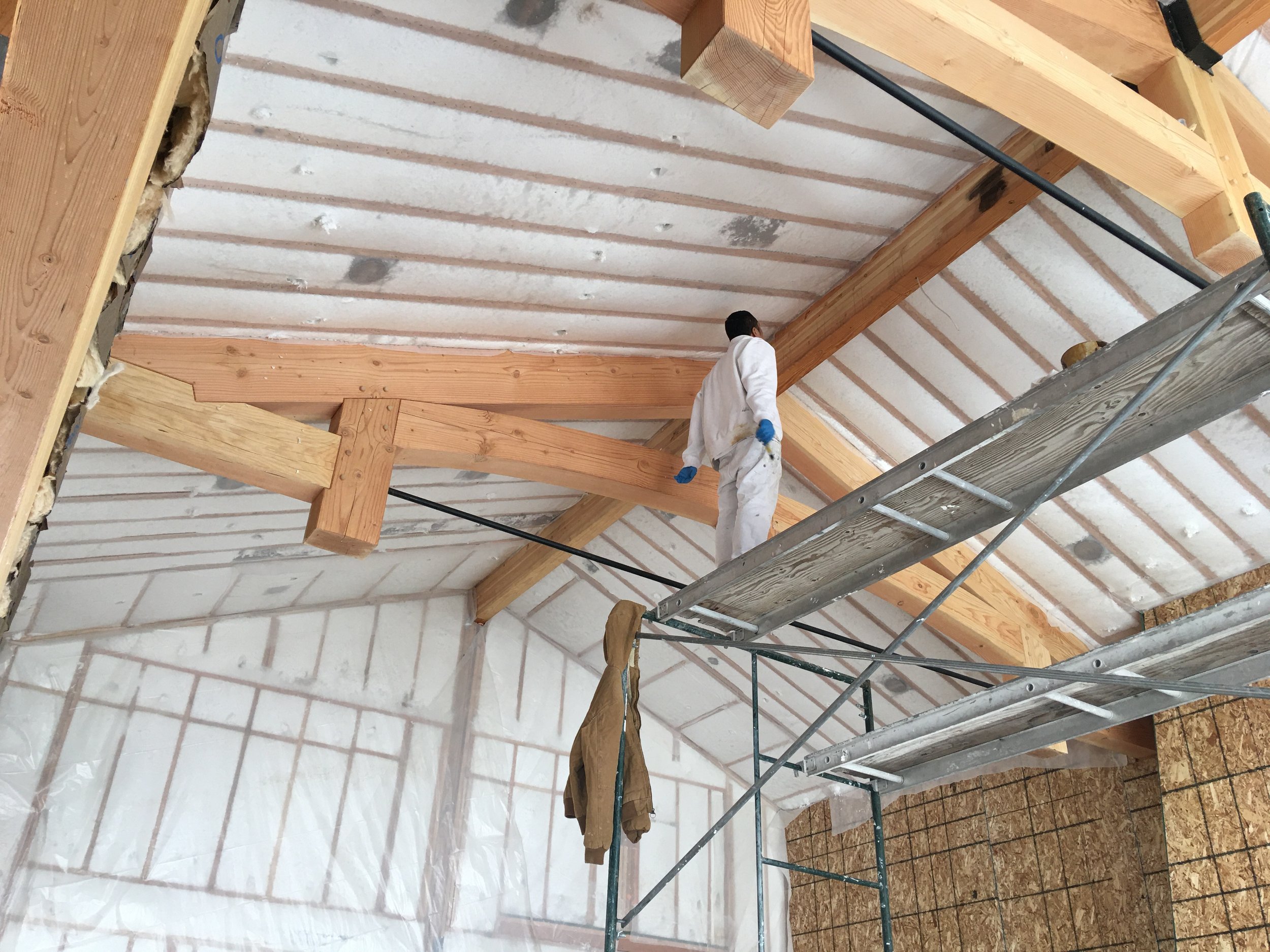 Exposed timber roof trusses with spray foam insulation installation
