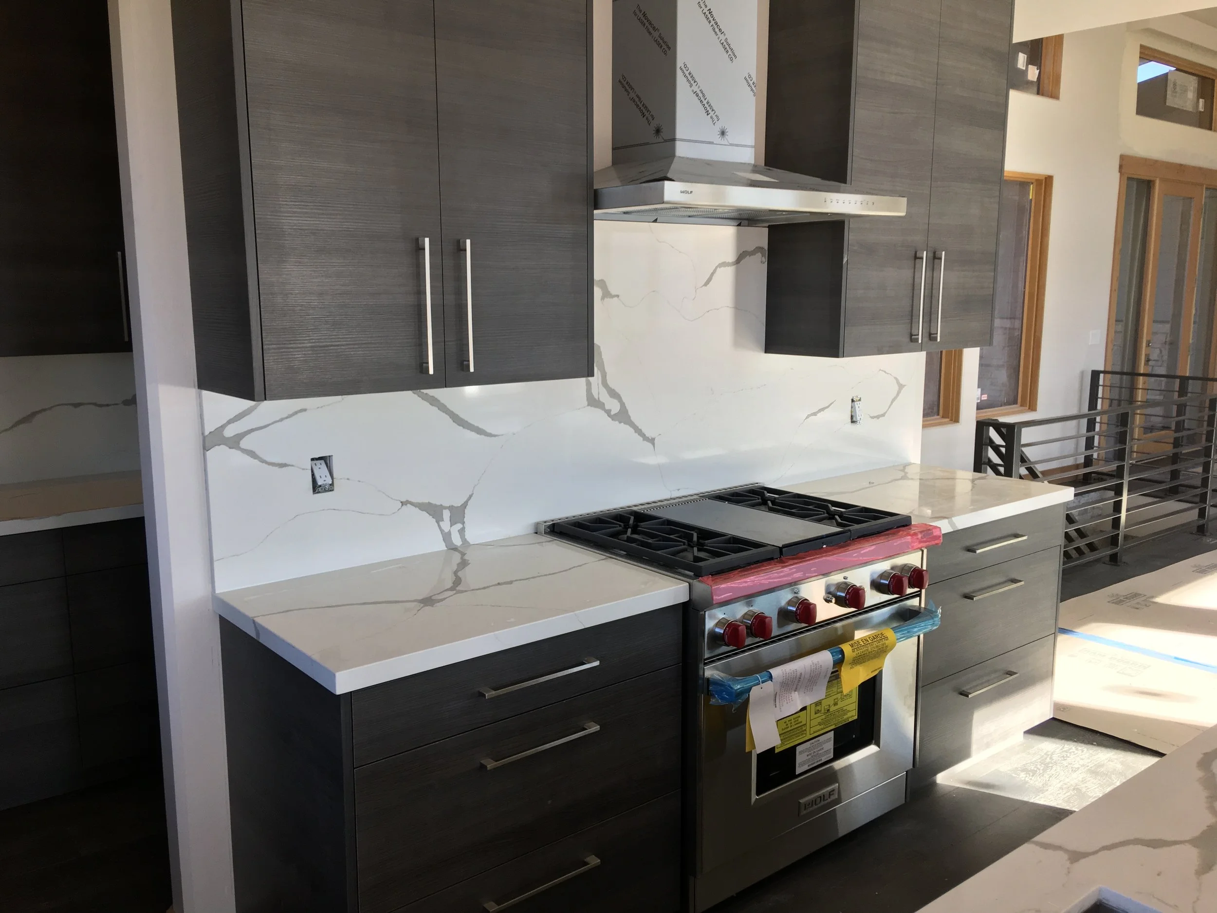 Custom kitchen with gray cabinetry, quartz surfaces, and Wolf range