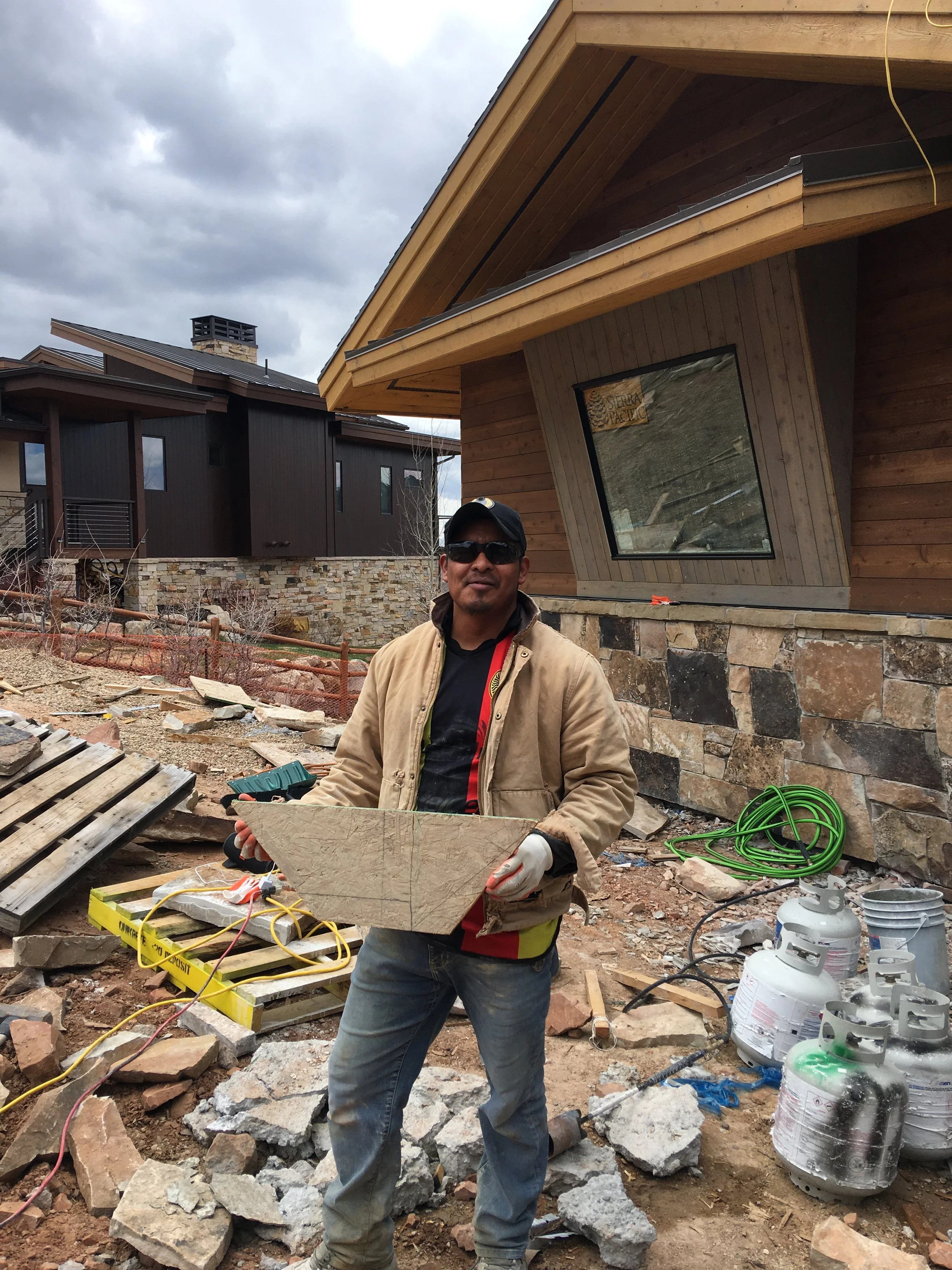 Mason hand-cutting natural stone veneer on home exterior
