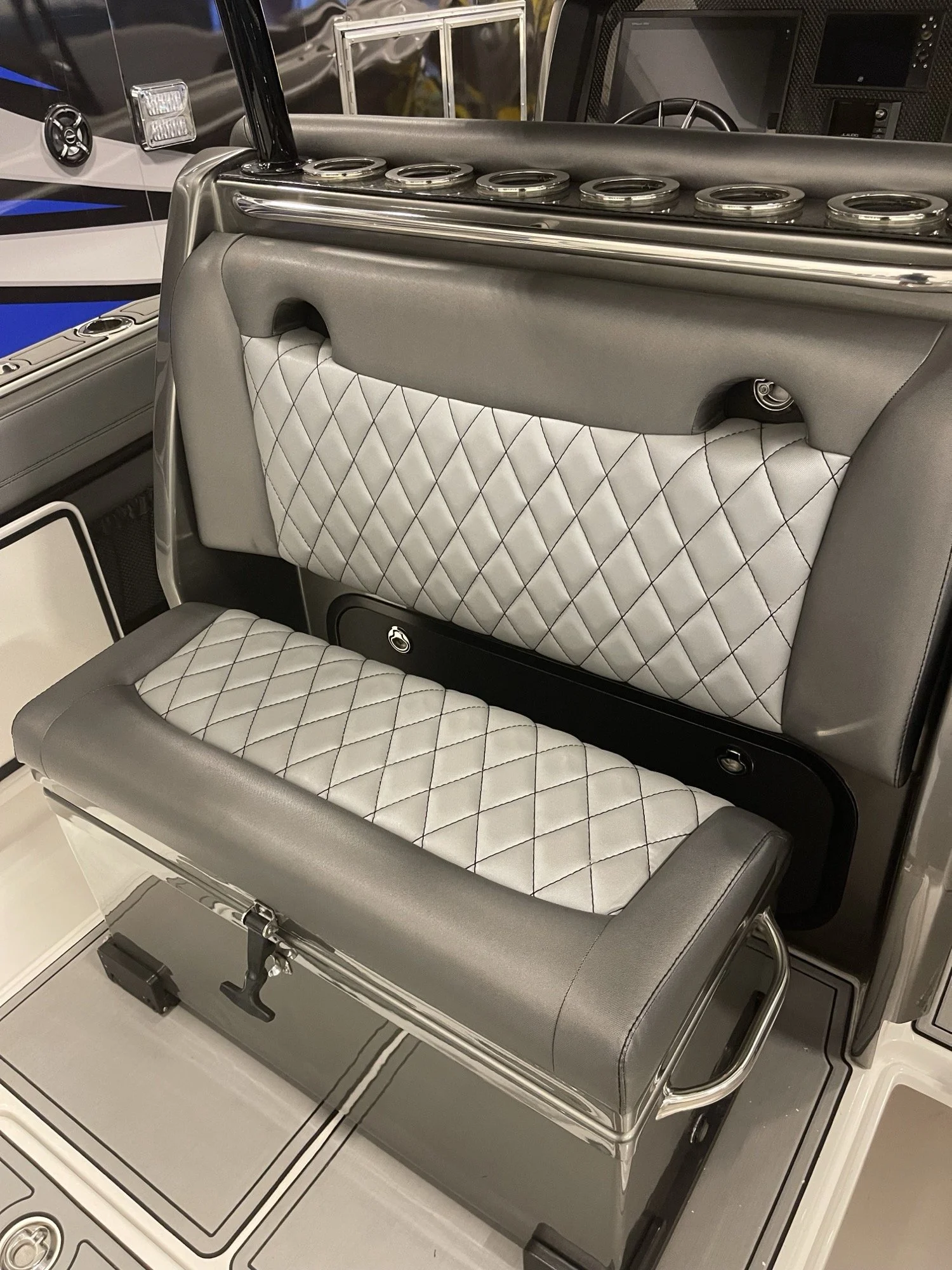 Helm bench and flip backrest in silver diamond-stitch vinyl, set behind a center console with rod holders and speakers