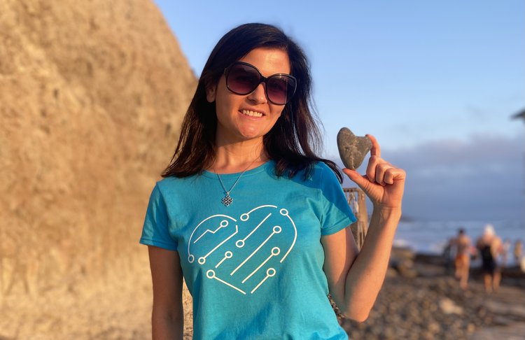 april in the compassionate coding shirt at the beach with a heart rock