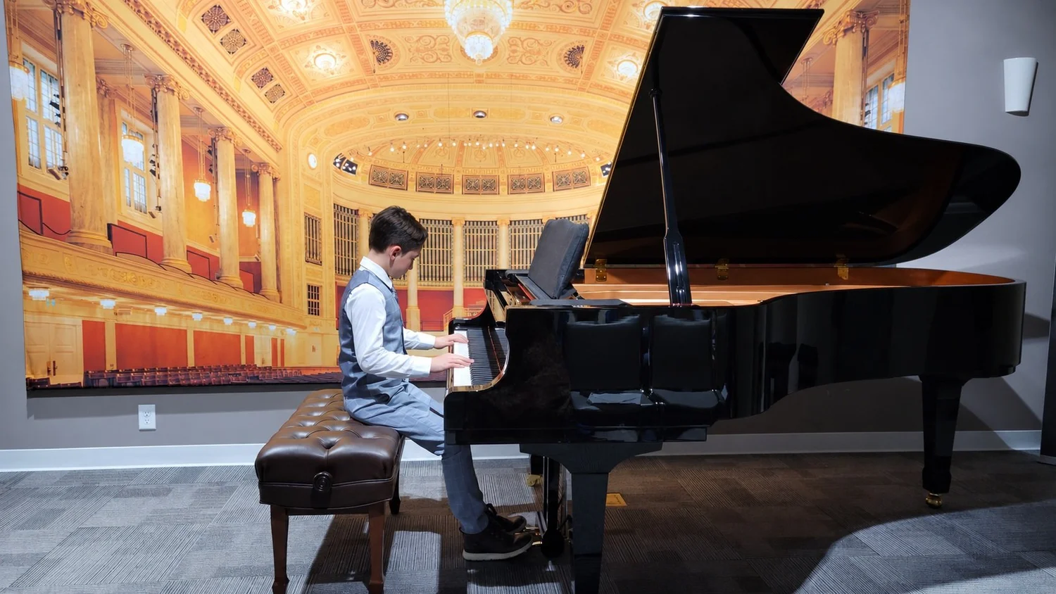 A Heart Beats student playing a grand piano beneath warm recital lights