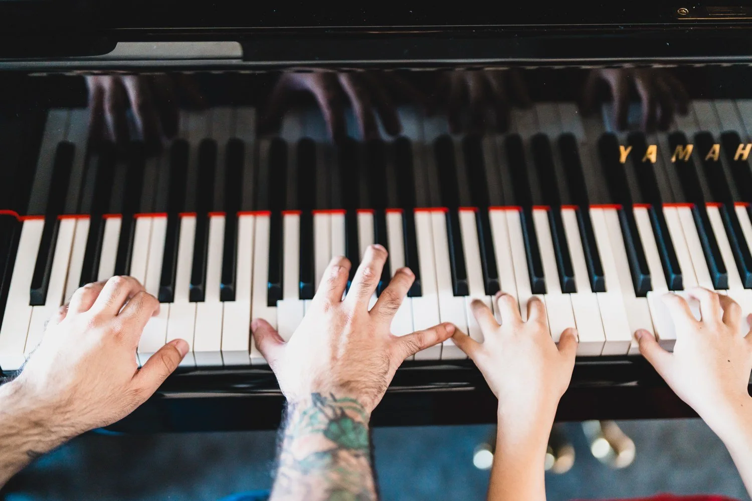 Teacher and student hands working together at a piano