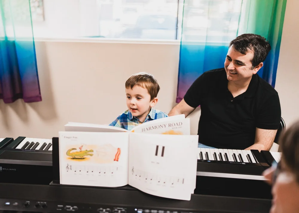 A grown-up and child singing and learning together at a keyboard in the Rainbow Room