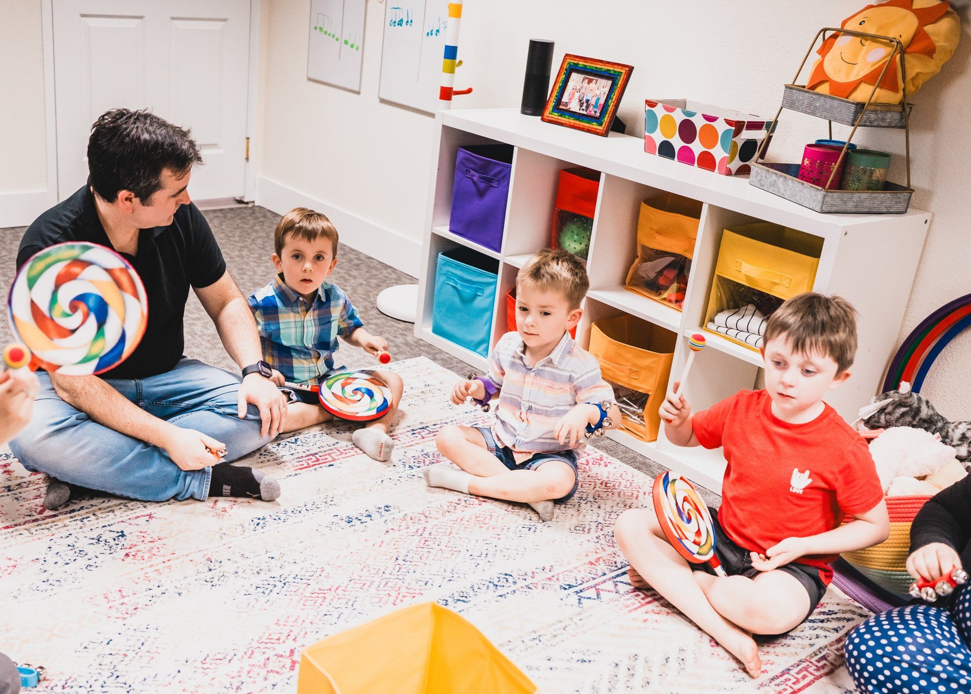 Children and a parent making rhythms together on colorful drums