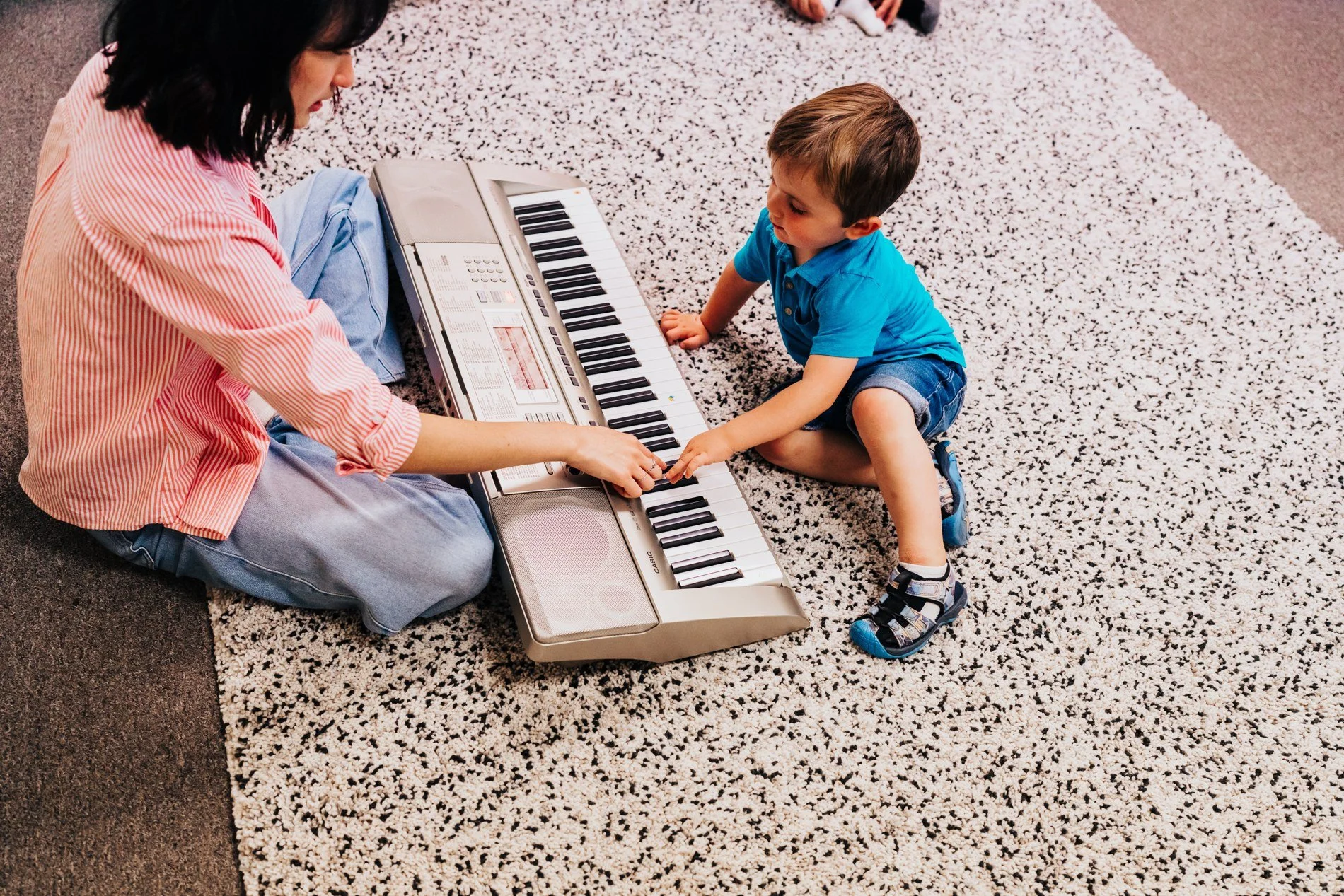 A child discovering a keyboard on the floor with a grown-up