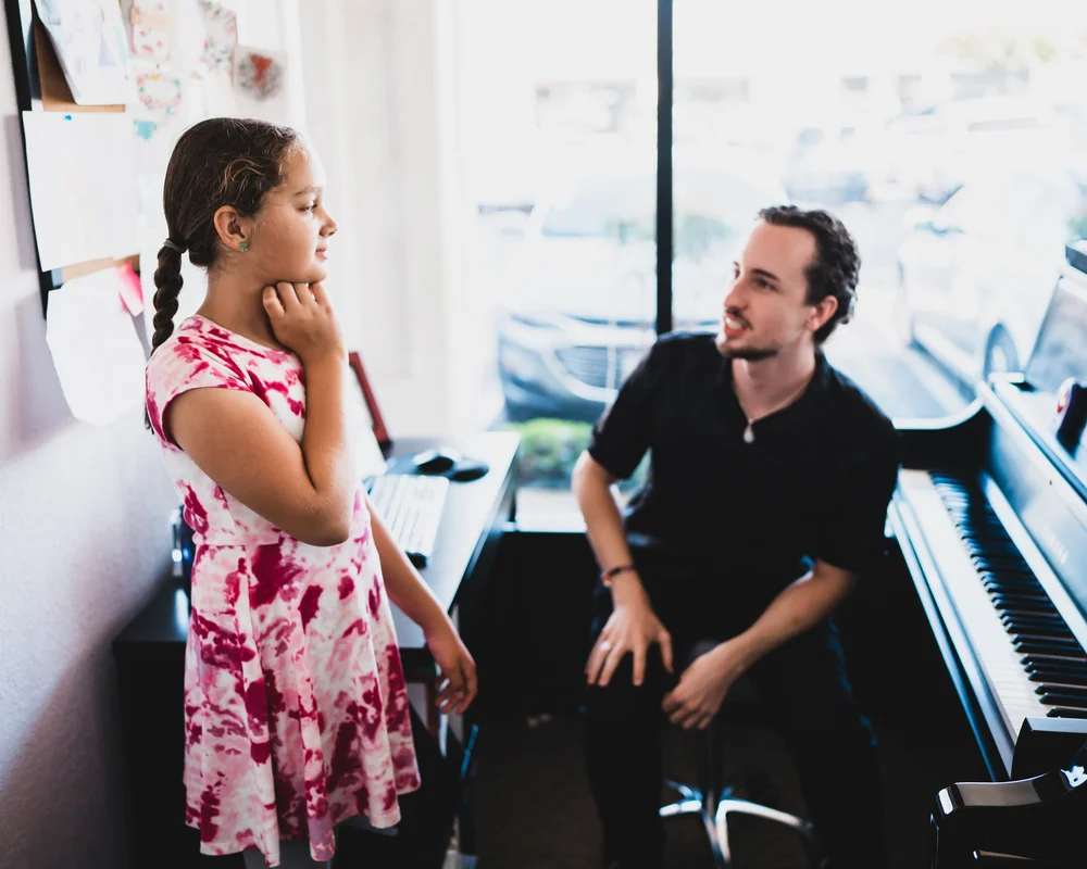 A voice student exploring a hand-at-the-jaw exercise while her teacher listens