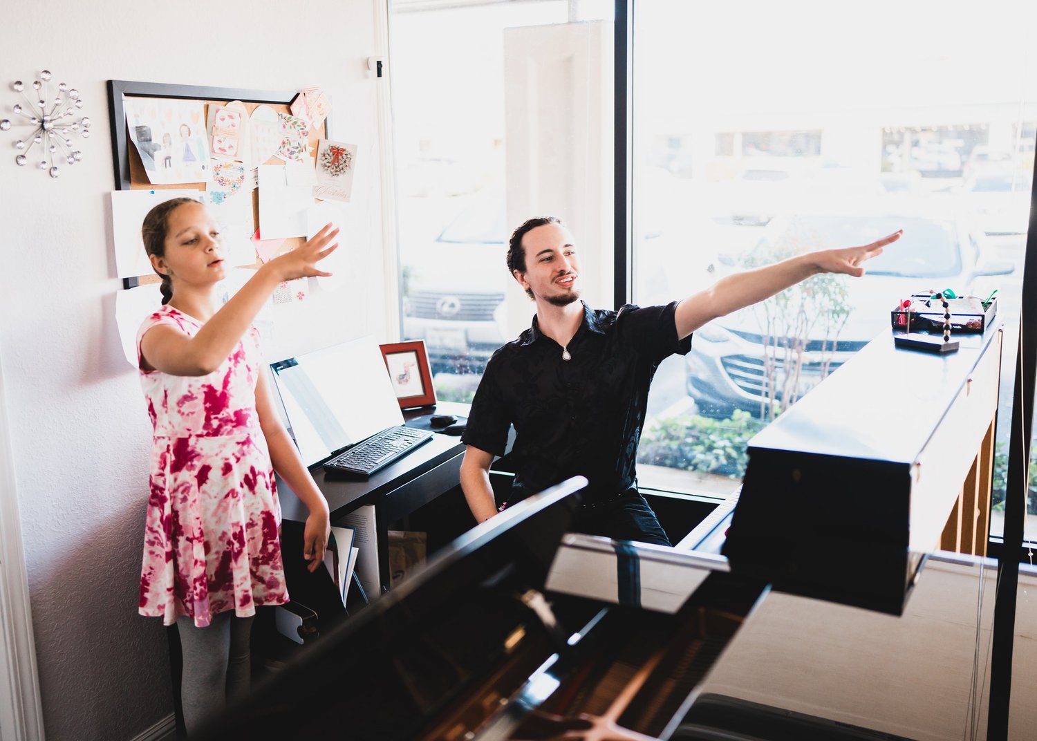 A voice teacher and student modeling an extended arm gesture together during a lesson