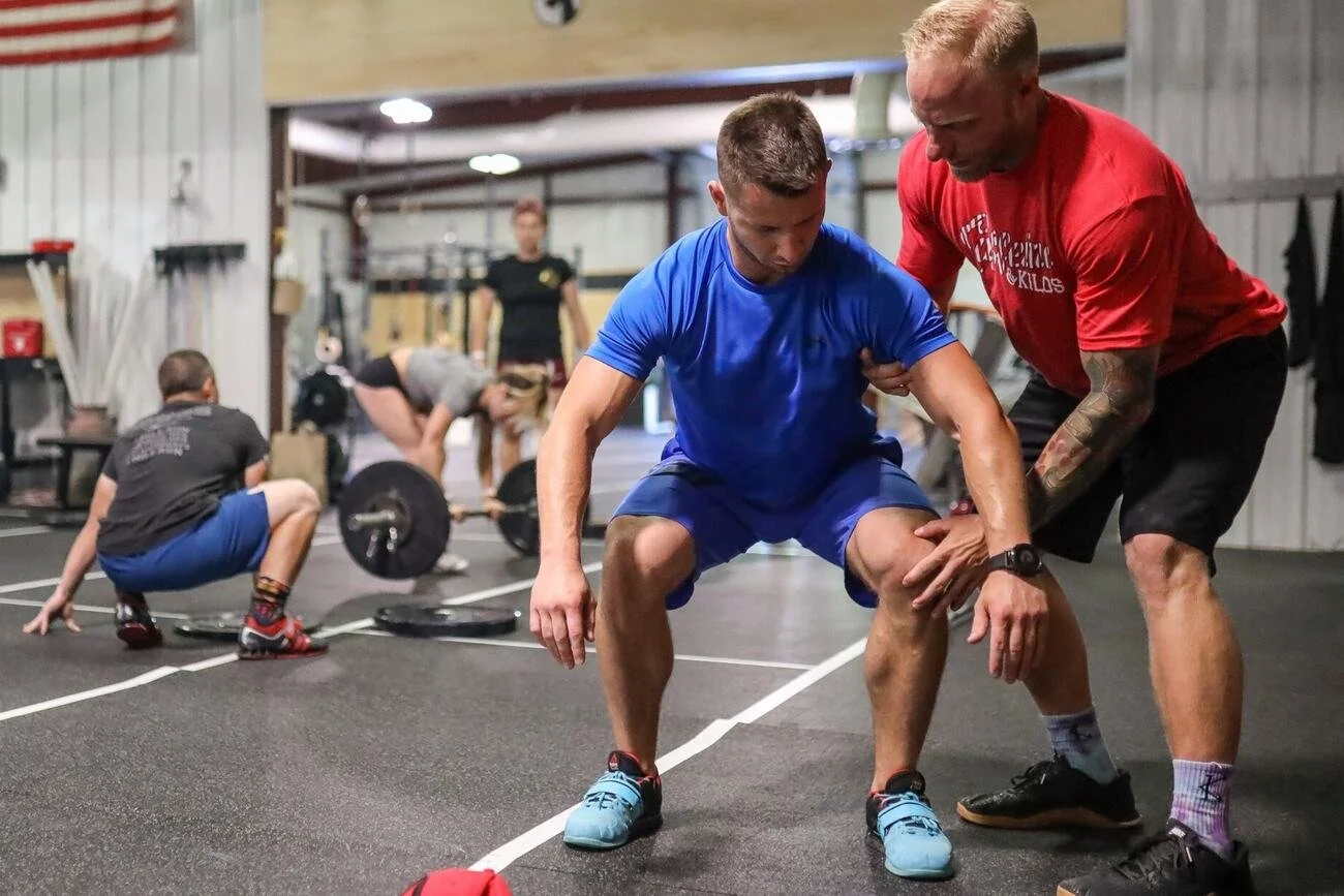 Danny Lehr coaching a lifter through a squat position on the platform