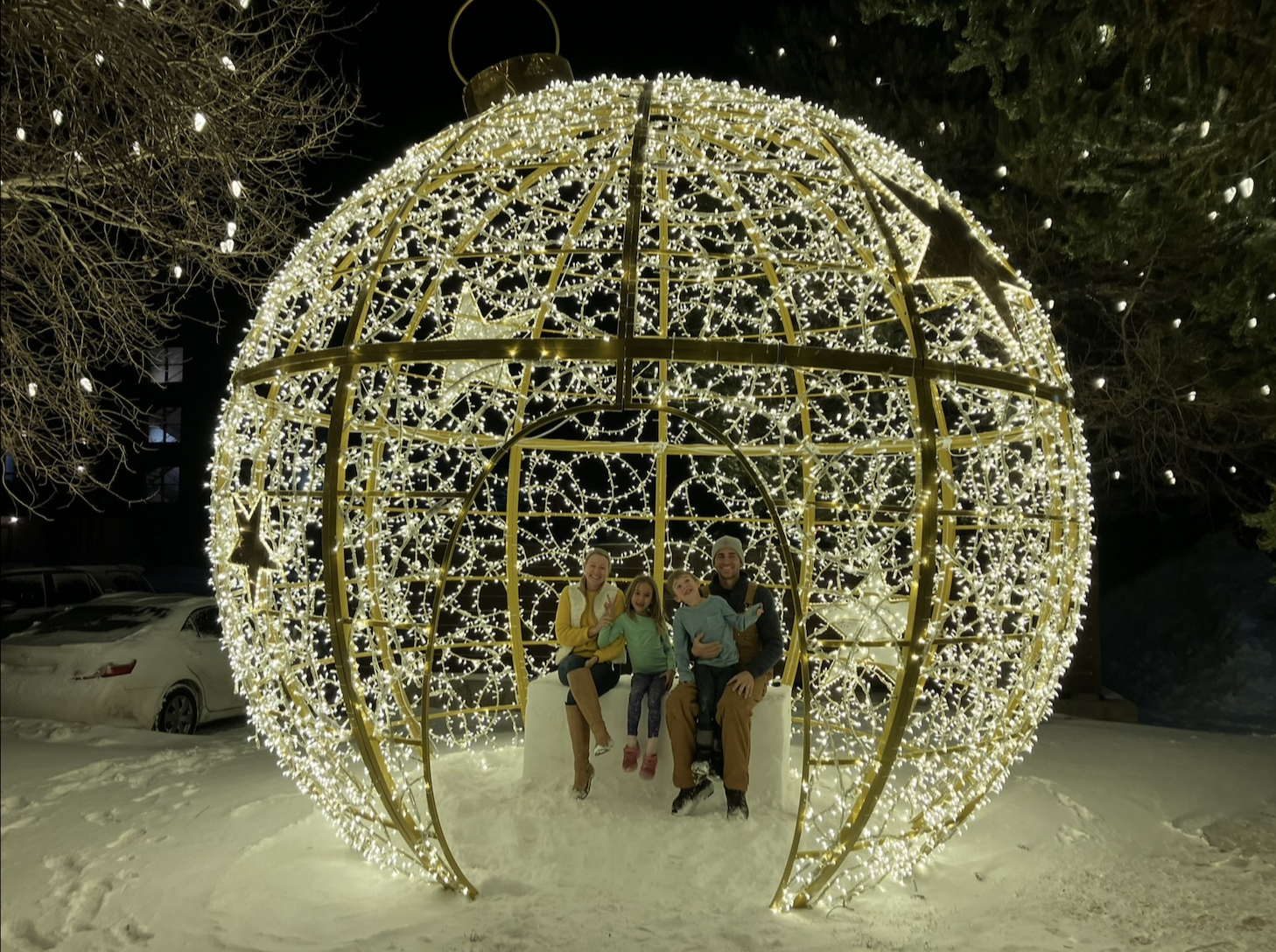 Family enjoying a large illuminated holiday ornament photo moment