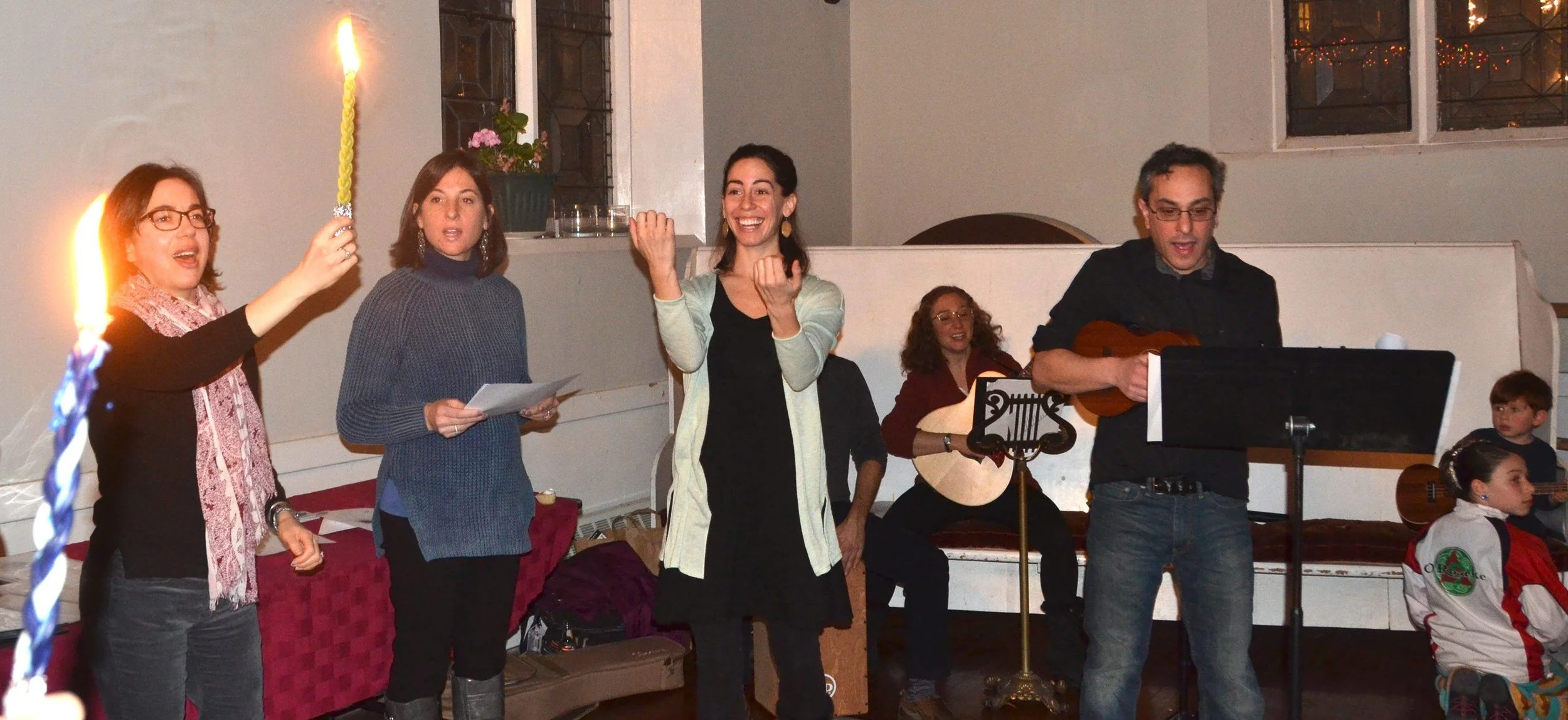 A Shtiebel havdalah: singers, a braided candle held aloft, ukulele and oud, children sitting in.