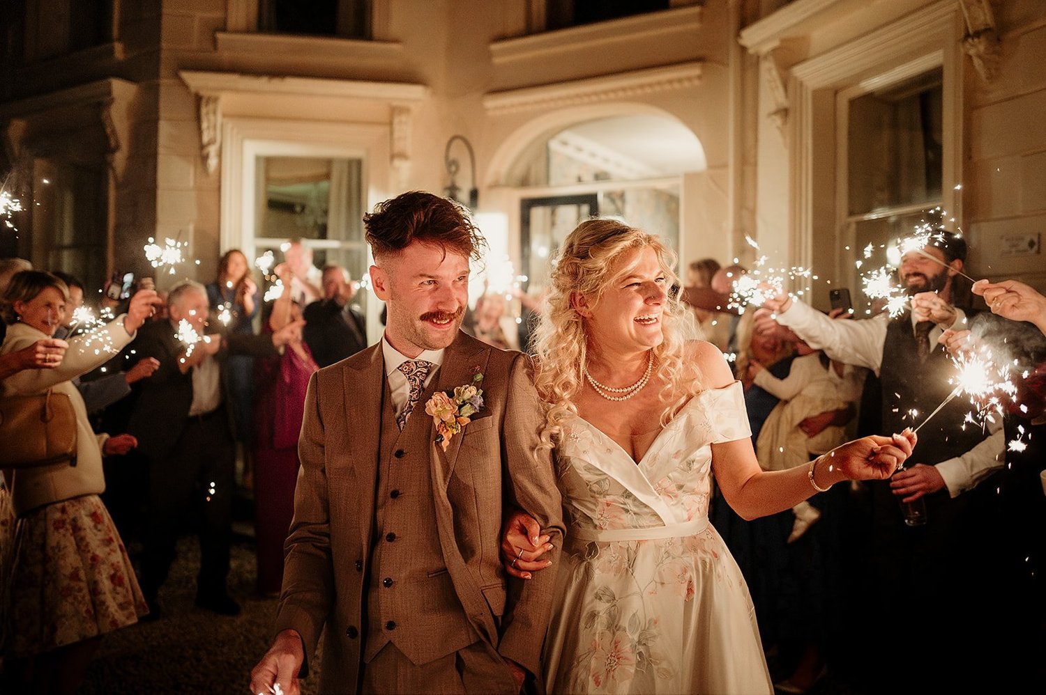 Jayne and Glen walking through a tunnel of sparklers held by their guests